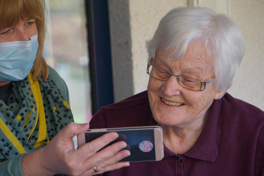 Woman in brown button up shirt holding a white smartphone